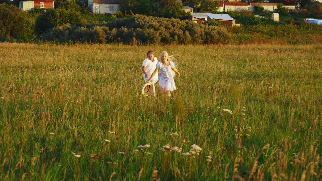 Duas Meninas Felizes Correndo por um Campo Gramado ao Pôr do Sol.
