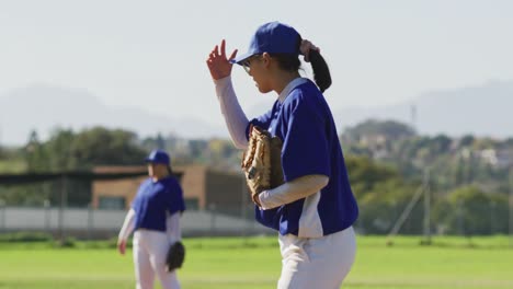 Disappointed-caucasian-female-baseball-player-holding-head,-crouching-on-field-after-losing-a-game