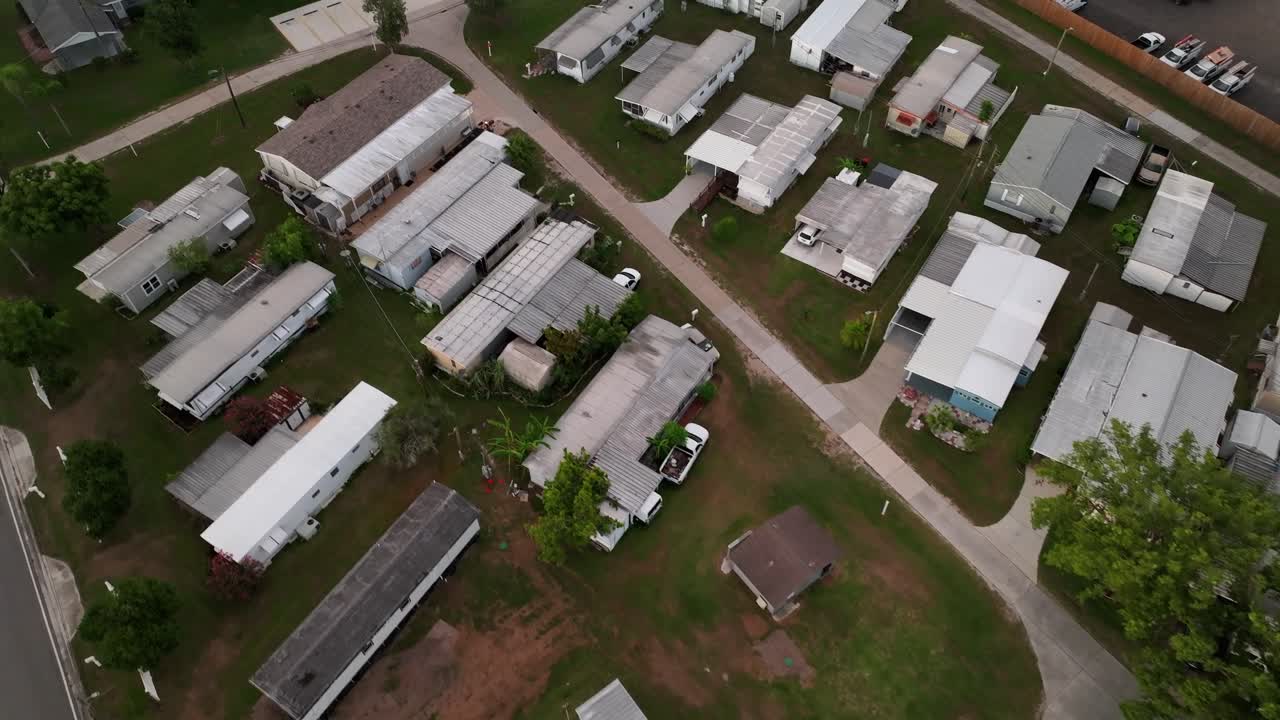 Drone flight over American mobile trailer homes in Florida. Aerial flyover shot. Dense population in cheap low income neighborhood at suburbia. Top down.