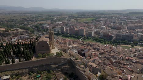 una hipnótica vista circular del avión no tripulado captura el esplendor de la iglesia católica santa maría de balaguer en lleida, españa, iluminada por el sol de la tarde