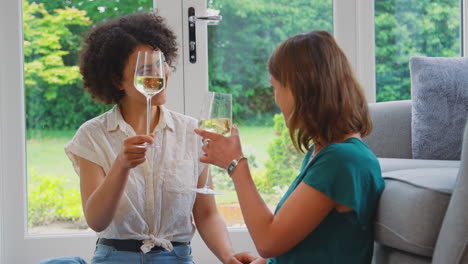 Same-Sex-Female-Couple-Or-Friends-At-Home-Relaxing-In-Lounge-Drinking-Wine-Together