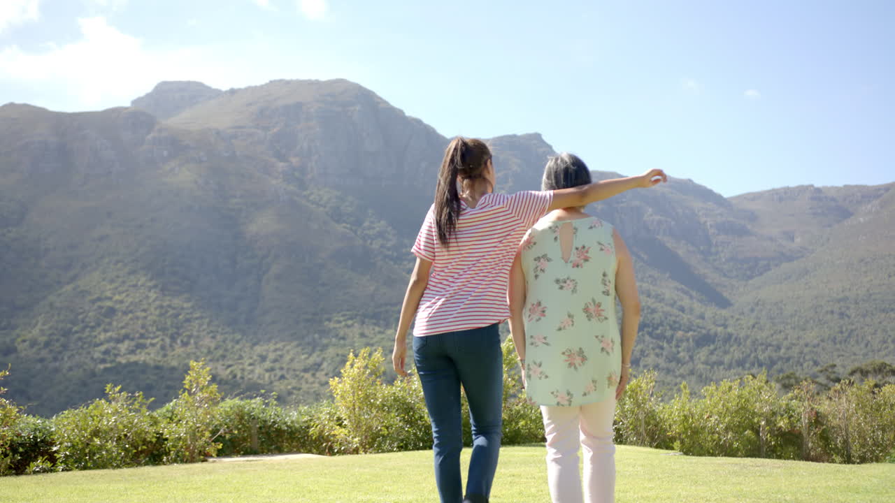 Embracing, asian grandmother and granddaughter enjoying scenic mountain view outdoors
