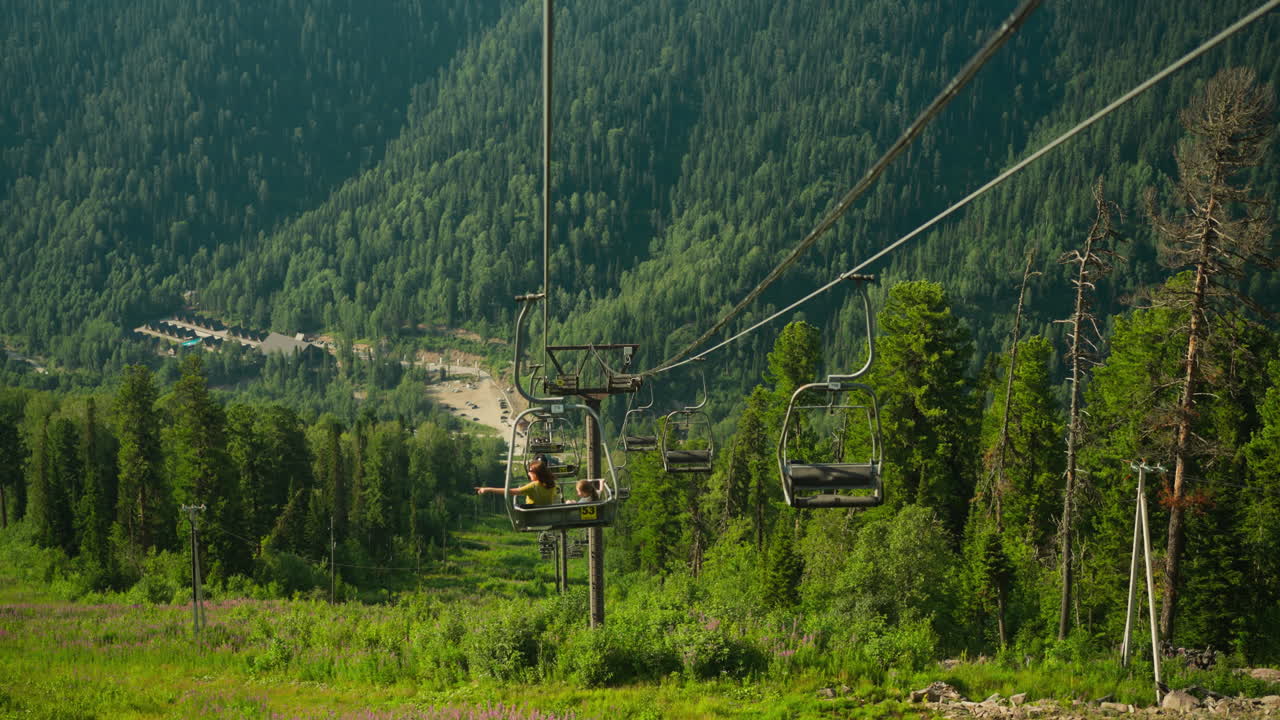 Viaggiatori in funivia che si godono una vasta area forestale. Discesa con vista mozzafiato su conifere e montagne. Vacanza estiva nella natura incontaminata.