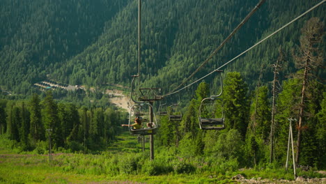 travellers ride cable car enjoying vast forest area. descent with breathtaking view of coniferous trees and mountains. summer vacation in untamed nature