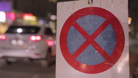 No parking sign in the night with passing traffic in the background