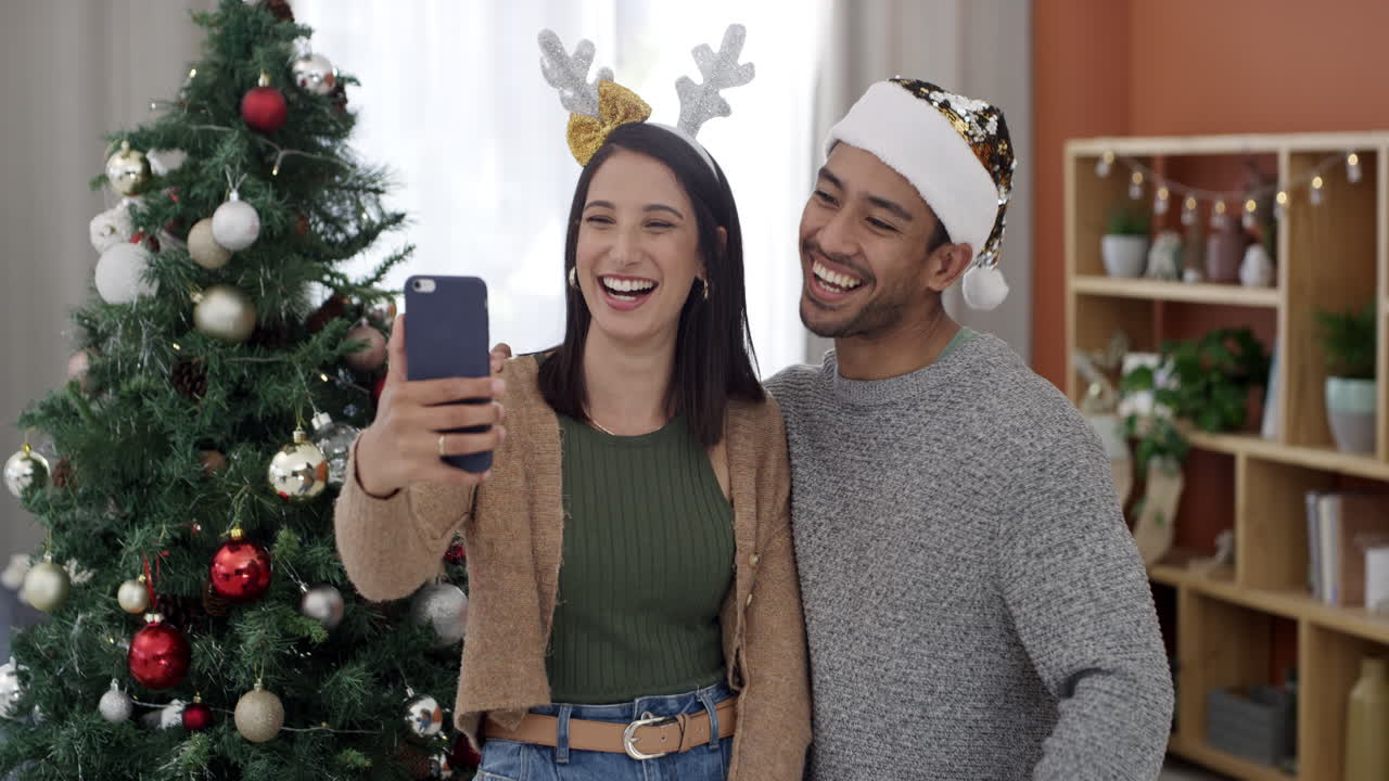 una pareja tomando una selfie junto al árbol de navidad.