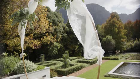 wedding arch with decorations in sunny summer garden with swimming pool, in slow motion