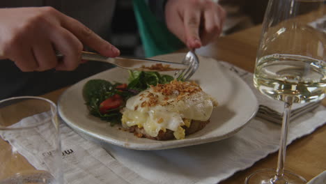 close-up of a person eating croque madame with salad