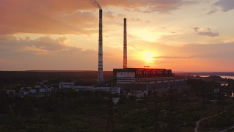 factory in the evening. dirty emissions from industrial pipes filling the air at sunset. ecological problems. aerial view. camera rising up.