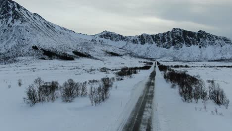 Vista-De-Drones-En-La-Zona-De-Tromso-En-Invierno-Levantándose-Del-Suelo-Mostrando-Una-Carretera-Estrecha-En-Medio-De-Un-Paisaje-Nevado-En-Noruega