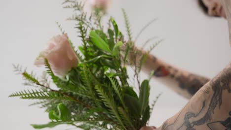 sosteniendo un ramo de flores y vegetación en un arreglo