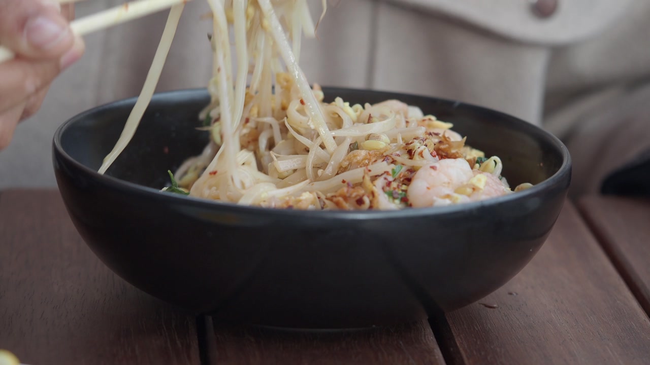 Mixing Pad Thai Noodles with Shrimp and Bean Sprouts in a Bowl