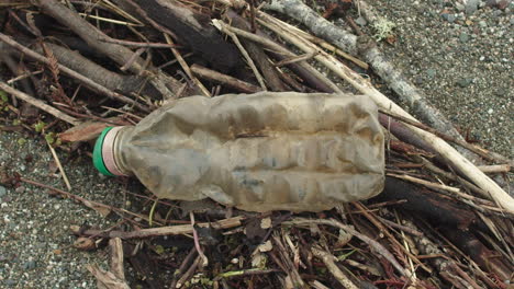 primer plano de una botella de plástico en la playa mientras la cámara gira de izquierda a derecha