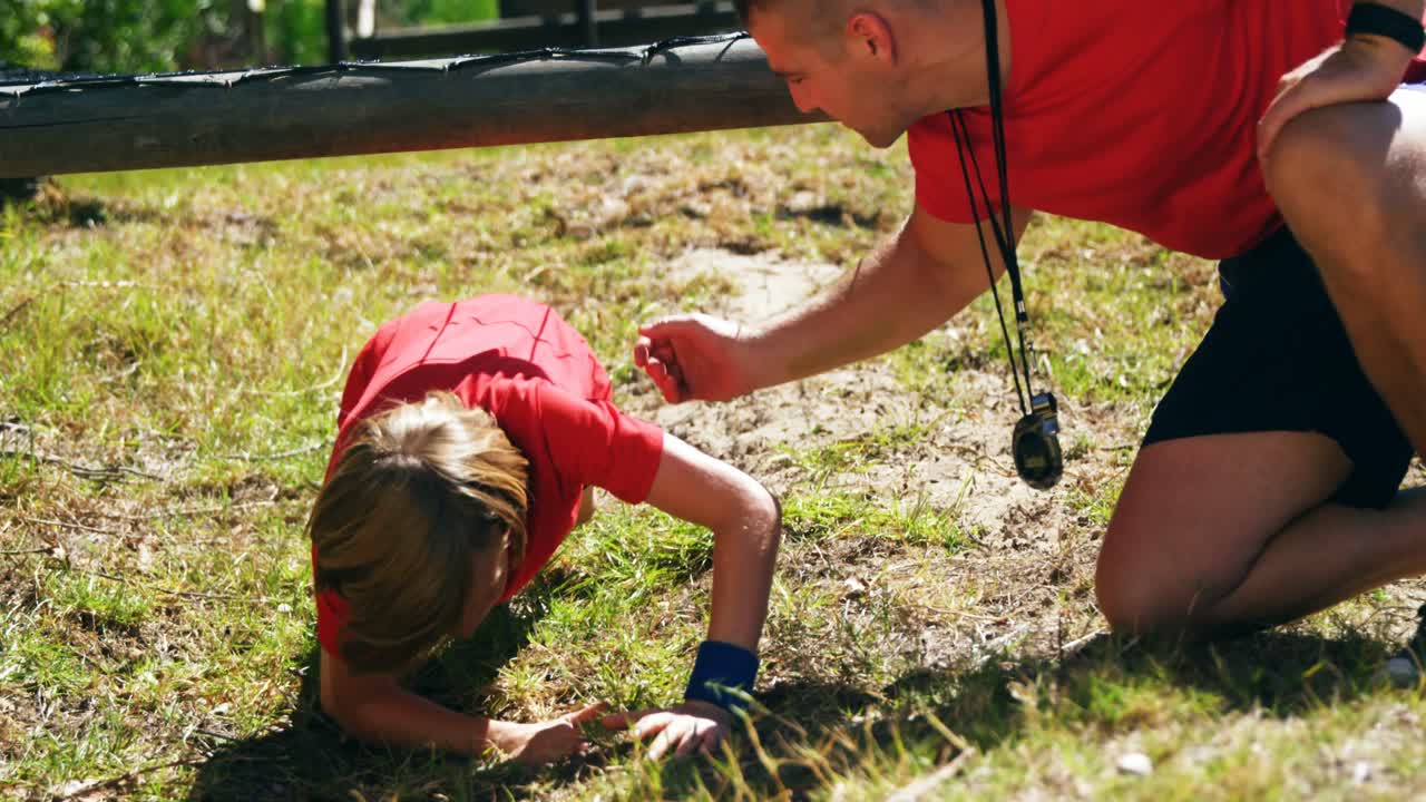 niños arrastrándose debajo de la red durante el entrenamiento de cursos de obstáculos