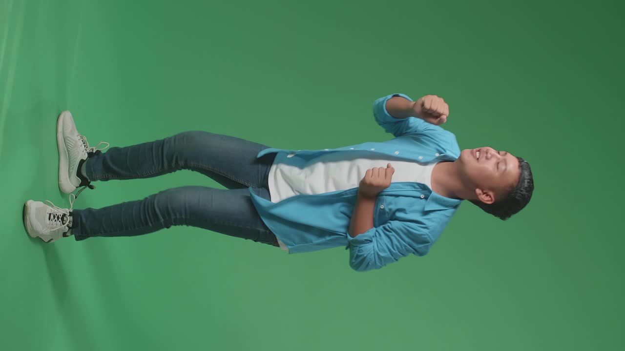 Side View Of Young Asian Man Dancing In A Green Screen Studio. Full Body