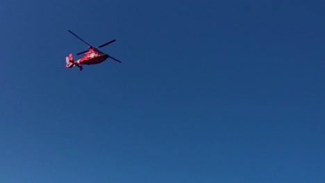 A-red-helicopter-chopper-flies-overhead-with-golden-gate-bridge-in-the-background,-San-Francisco,-California,-USA