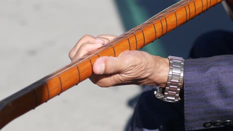 elderly man playing a turkish saz