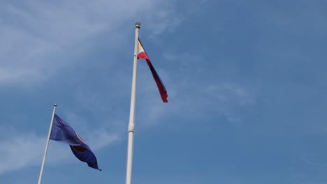 philippine national flag and the asean flag flying together at the philippine embassy in bangkok, thailand with blue lovely sky and some clouds