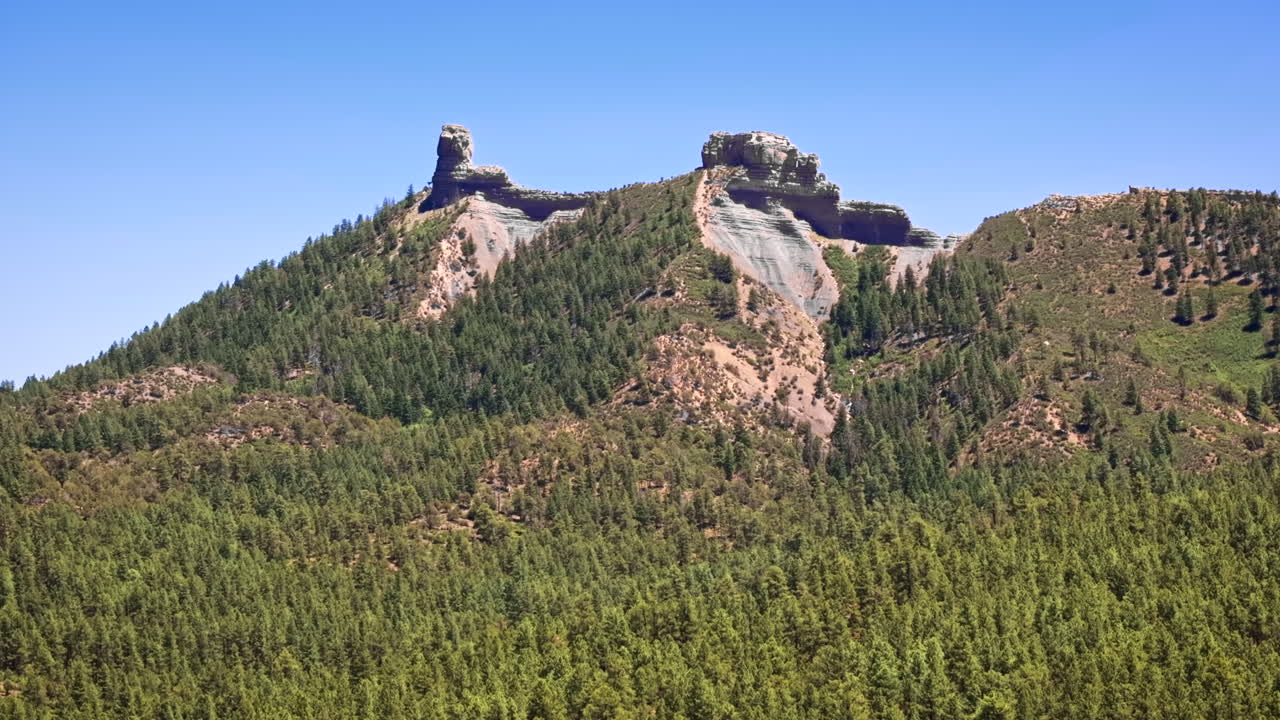70 mm filmisk flygdrönarbild av Chimney Rock nära Owl Creek Pass i Uncompahgre National Forest, nära Pagosa Springs, Colorado, inramad av oländig alpin terräng och taggiga toppar