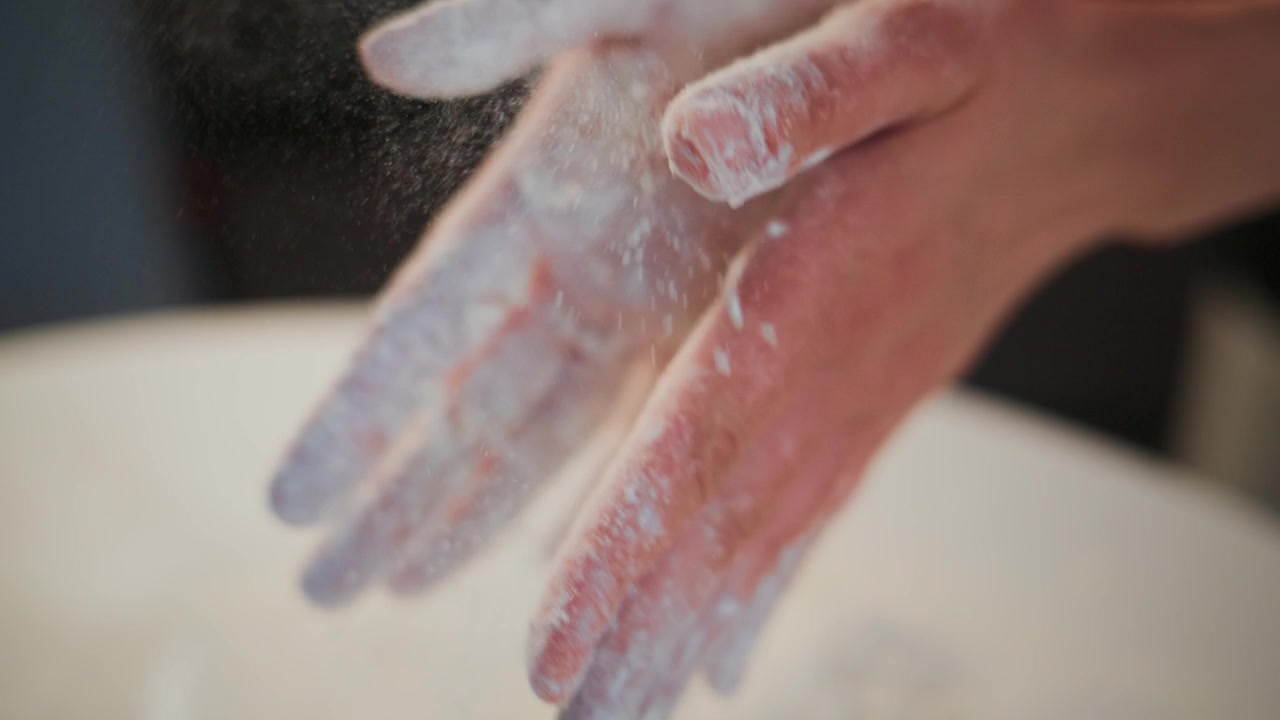 Primo piano di mani che impastano. La farina ricopre le dita mentre l'impasto prende forma. Le mani lavorano con costanza, concentrate sulla modellatura. Perfetto per video di cucina, panificazione o preparazione alimentare. Ideale per contenuti culinari, ricette.