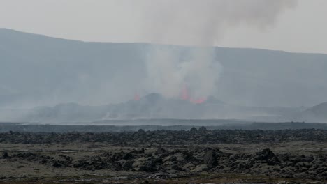 vista lejana del volcán grindavik en erupción en el cráter sundhnúkur, islandia, con humo y lava visibles