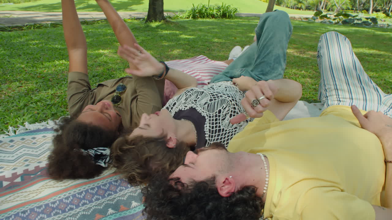 Friends Taking Selfie with Phone on Green Grass in Park