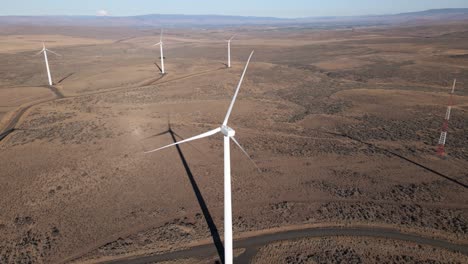 long shadows stretch across the desert floor, orbiting a giant electric wind turbine, aerial panorama