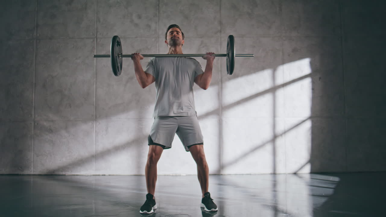 Muscular sportsman lifting weights in gym. Sporty powerlifter fitness workout