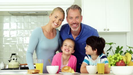 portrait of smiling family standing in kitchen