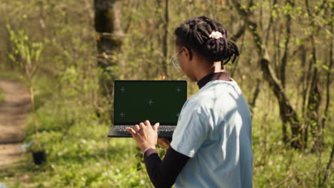 niña afroamericana limpiando el bosque y usando una pantalla de portátil aislada