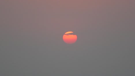 sunset with a small cloud covering part of the sun. mount abu, rajasthan, india.