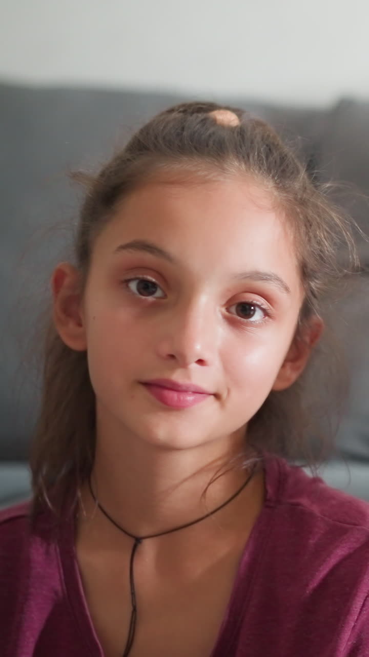 Vista de retrato de niños preciosos sentados en el interior mirando directamente a la cámara con expresiones suaves mientras el niño sonríe levemente y la niña mantiene un rostro tranquilo, ambos con un aspecto sereno sobre un fondo acogedor.