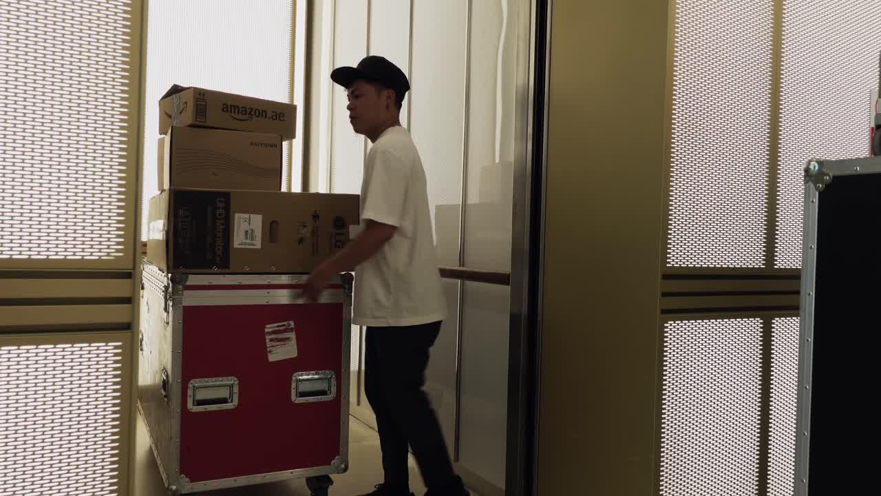joven asiático cargando maletas en un ascensor y las puertas cerrándose detrás de él