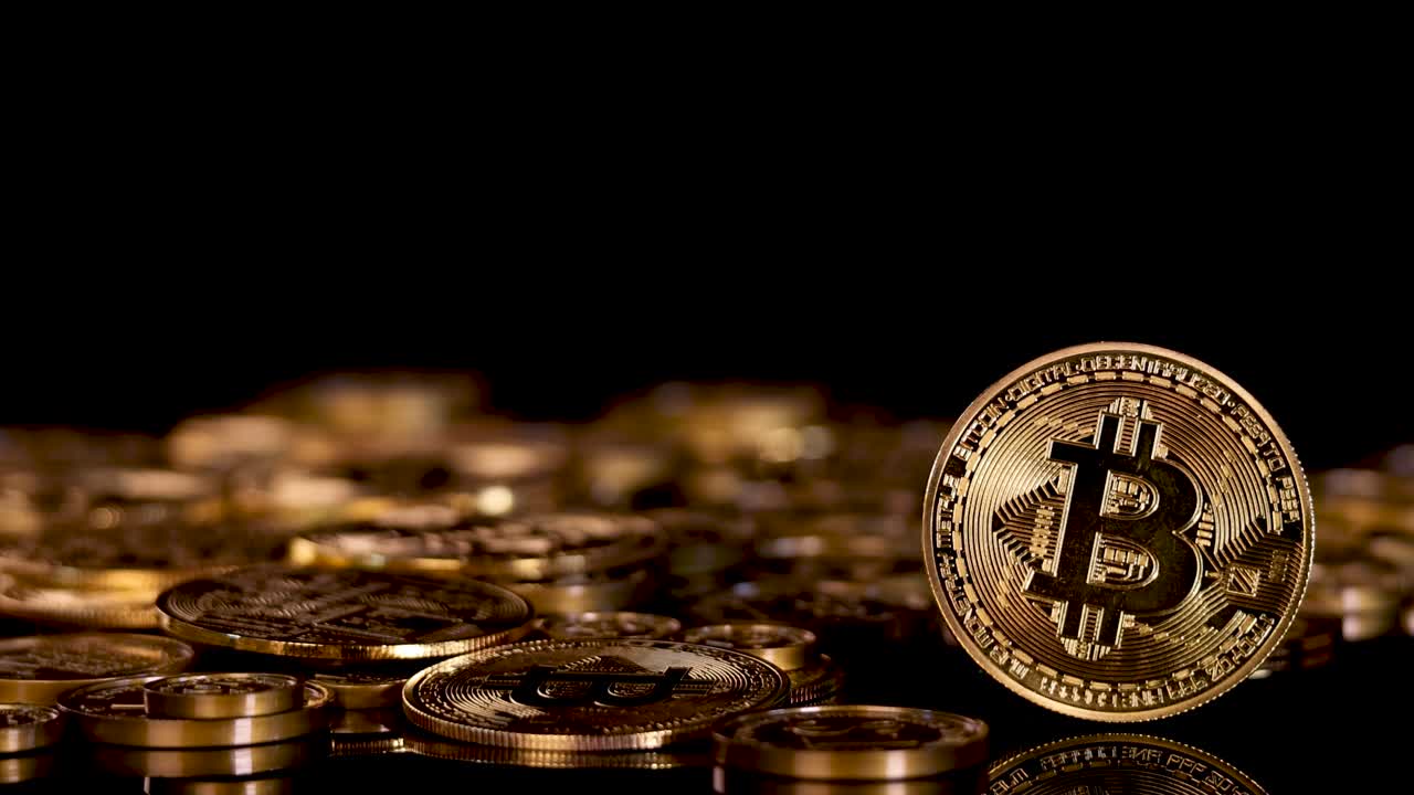 Gold Bitcoin lands upright on a coin pile under dramatic studio lighting