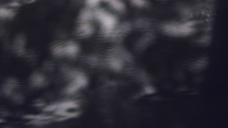 Blurry shots of raindrops falling on a footpath in a shiny rain puddle - close up