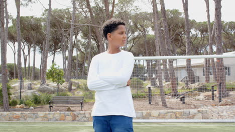 teen boy standing on soccer field, looking away with thoughtful expression, copy space