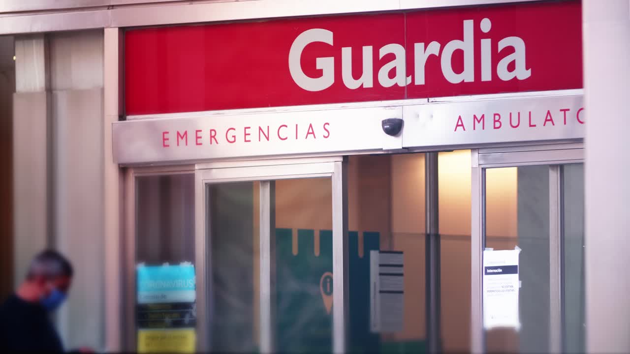 Persona con mascarilla en la entrada de emergencias de un hospital