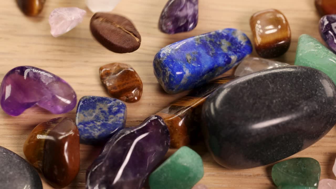 Várias pedras de chakra espalhadas sobre uma superfície de madeira, exibindo cores e texturas vibrantes sob iluminação suave.