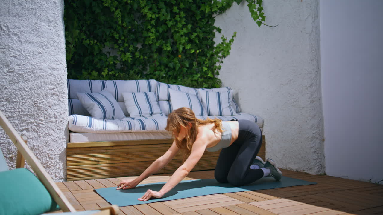 Slim girl practicing pilates at patio. Sporty woman performing yoga