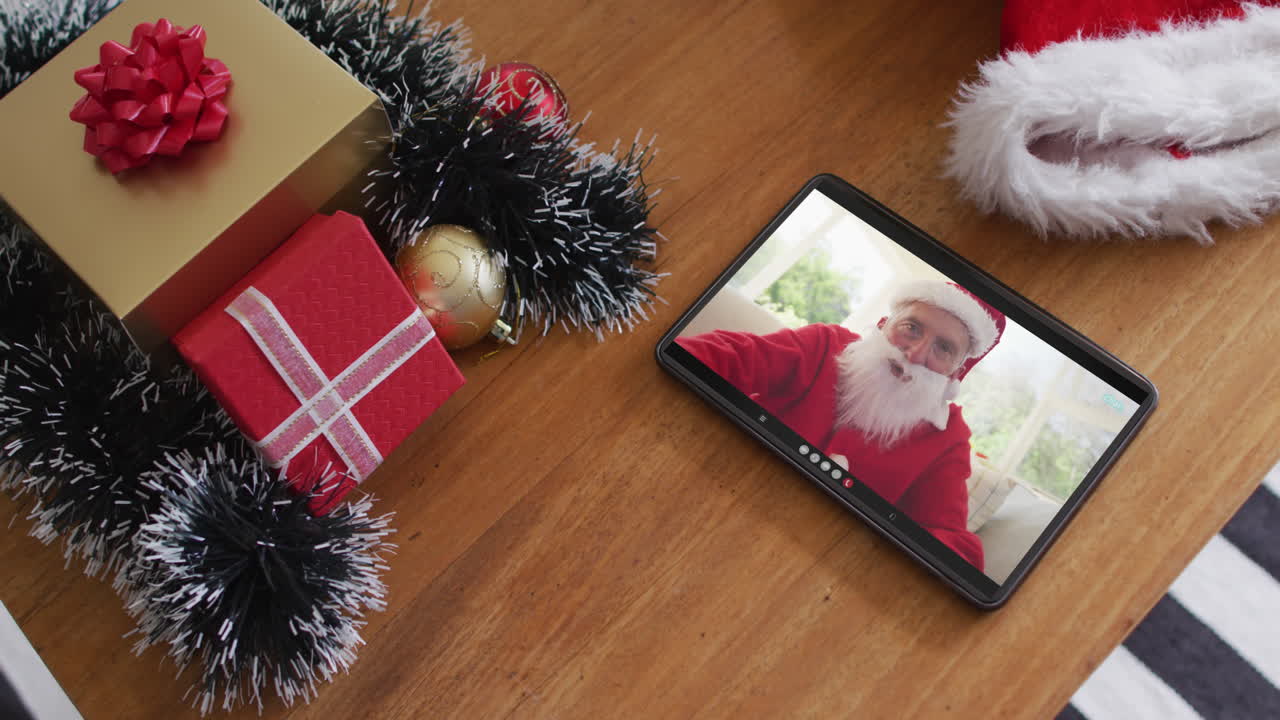 hombre caucásico sonriente vestido con disfraz de santa en una videollamada de navidad en una tableta