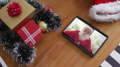 hombre caucásico sonriente vestido con disfraz de santa en una videollamada de navidad en una tableta