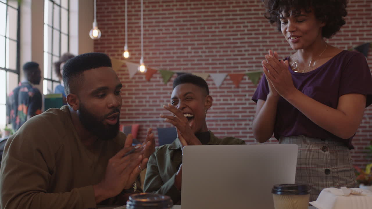 group of business people celebrating corporate success black colleagues laughing clapping cheerful enjoying successful victory watching laptop in modern office workplace