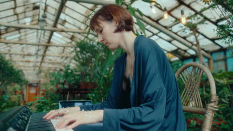woman with gem decorations on hands playing synthesizer in orangery