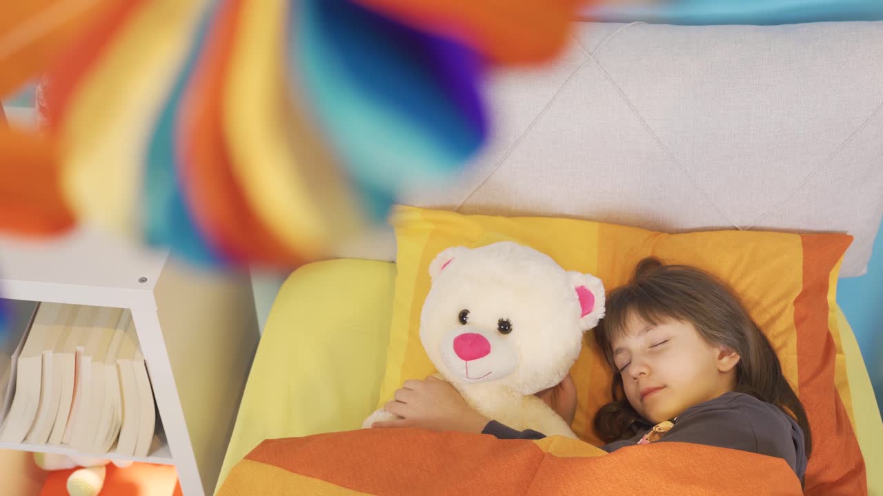 작은 소녀가 장난감과 함께 침대에서 잠을 자고 있습니다.