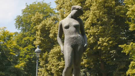 a beautiful capture of a bronze statue depicting a naked woman instead a park