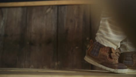 toddler boy slowly walks right along wooden bench in hut, close up