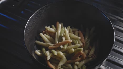 pouring hot boiled fileja pasta into a bowl then add cream cheese, mayonnaise, and chopped bell peppers for dressing