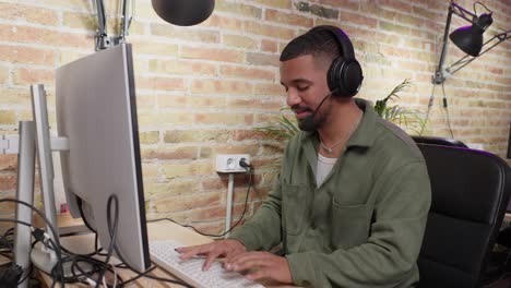 man working at a desk with computer and headphones