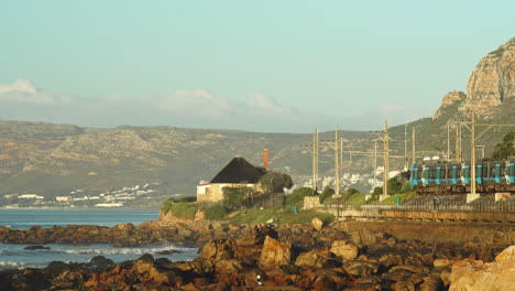 Metro-Train-Driving-Past-Ocean-on-Beach-Side-Railway---Wide-Shot,-Morning