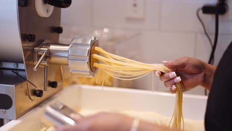 Chef-Femenina-Haciendo-Espaguetis-Caseros-Con-Una-Máquina,-Apretada